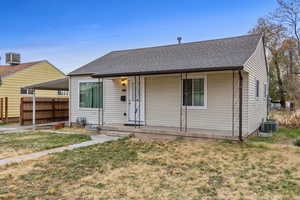 Bungalow featuring central air condition unit, covered porch, and a front yard