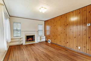 Unfurnished living room featuring hardwood flooring and wooden panel walls