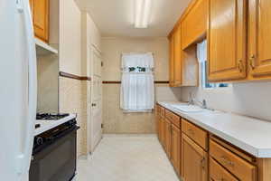 Kitchen featuring white fridge, sink, and black and white range with gas cooktop