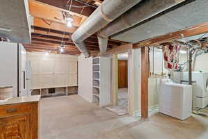 Basement featuring white refrigerator separate washer and gas dryer