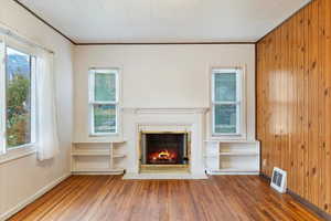 Unfurnished living room with plenty of natural light, hardwood flooring, and a fireplace