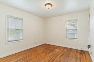 Empty room with hardwood  and a healthy amount of sunlight