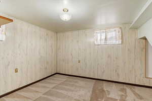 Unfurnished room featuring wood walls and New light colored carpet