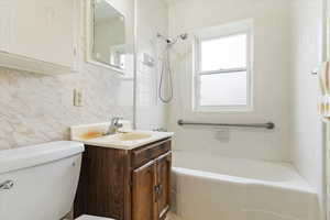 Full bathroom featuring tiled shower / bath combo, backsplash, toilet, vanity