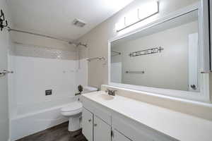 Full bathroom with hardwood / wood-style floors, vanity, toilet, and tiled shower / bath combo