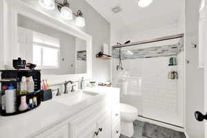 Bathroom with vanity, a shower with shower door, and toilet