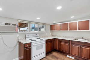 Kitchen featuring a wall mounted air conditioner, light stone countertops, white electric range oven, sink, and dark hardwood / wood-style floors