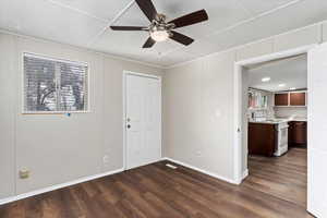 Empty room featuring ceiling fan and dark hardwood / wood-style flooring