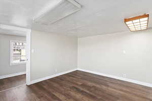 Empty room with dark hardwood / wood-style flooring