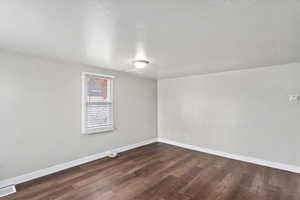 Empty room featuring dark wood-type flooring