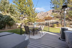 Wooden terrace featuring a mountain view, a yard, and a hot tub