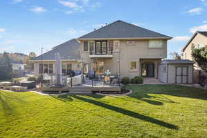 Rear view of house featuring a shed, a deck, hot tub, fire pit and yard