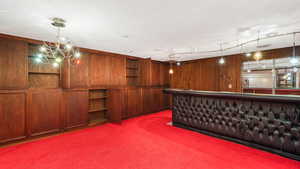 Bar with carpet flooring, pendant lighting, a textured ceiling, and an extensive storage cupboard built into the wall