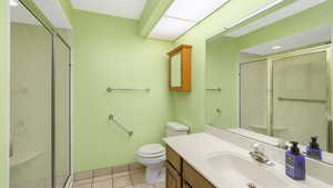 Bathroom with tile patterned flooring, vanity, toilet, and a shower with shower door