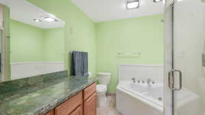 Full bathroom featuring tile patterned flooring, vanity, separate shower and tub, and toilet