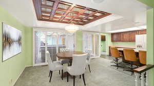 Carpeted dining room with a tray ceiling, an inviting chandelier, and coffered ceiling - Virtual staging