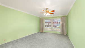 Empty room with crown molding, ceiling fan, and light carpet