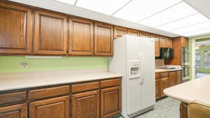 Kitchen featuring cooktop, white fridge with ice dispenser, and stainless steel double oven