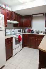 Kitchen with sink, white appliances, and light tile patterned floors