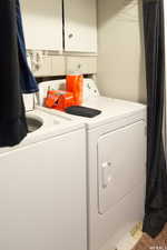 Laundry area with separate washer and dryer and cabinets