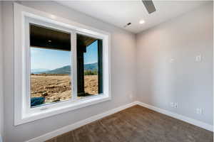 Carpeted spare room featuring a mountain view and ceiling fan