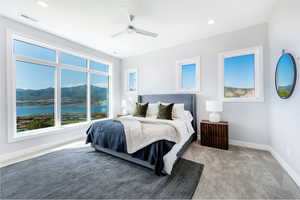 Bedroom featuring ceiling fan, a water and mountain view, and light carpet