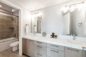 Full bathroom featuring vanity, bath / shower combo with glass door, and toilet