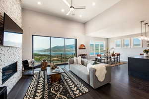 Living room featuring ceiling fan, dark hardwood / wood-style flooring, a towering ceiling, and a fireplace