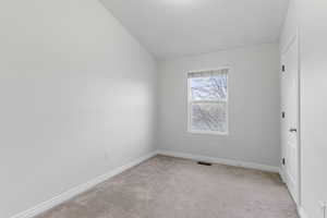 Carpeted empty room with lofted ceiling