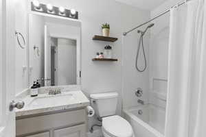 Full bathroom with vanity, shower / tub combo, and toilet