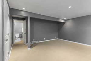 Basement featuring a textured ceiling and light carpet