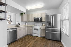 Kitchen featuring sink, dark hardwood / wood-style flooring, stainless steel appliances, and a textured ceiling