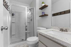 Bathroom featuring tile patterned flooring, vanity, toilet, and walk in shower