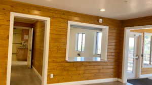 Doorway to outside with wood-type flooring, a healthy amount of sunlight, and wood walls