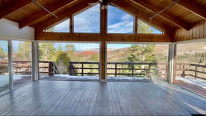 Unfurnished sunroom with vaulted ceiling with beams, ceiling fan, and wooden ceiling