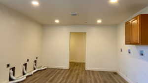 Clothes washing area featuring hookup for an electric dryer, cabinets, light wood-type flooring, and washer hookup