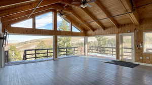 Unfurnished sunroom featuring vaulted ceiling with beams, ceiling fan, and wooden ceiling