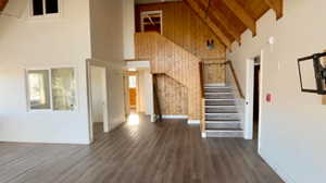 Stairway with wooden walls, beam ceiling, hardwood / wood-style flooring, high vaulted ceiling, and wooden ceiling