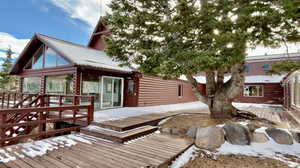 Snow covered house featuring a sunroom and a deck