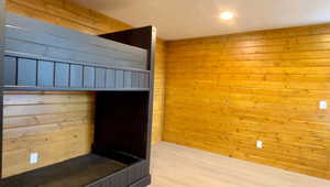 Unfurnished bedroom with hardwood / wood-style floors and wood walls