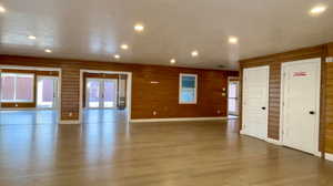 Unfurnished living room with wood walls, french doors, and hardwood / wood-style flooring