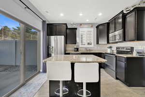 Kitchen with tasteful backsplash, a center island, granite countertops, stainless steel appliances, and light hardwood / wood-style flooring