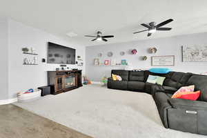 Living room with hardwood / wood-style flooring, ceiling fan, and a textured ceiling