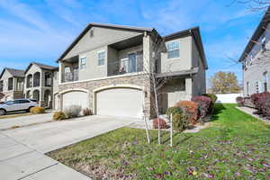 Townhome / multi-family property with a balcony, 2 car garage, and a front lawn