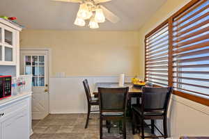 Dining space featuring ceiling fan, a healthy amount of sunlight, and wood walls