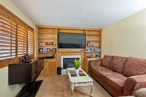 Living room featuring a tiled fireplace, a textured ceiling, and light hardwood / wood-style flooring