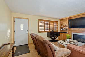 Living room featuring light wood-type flooring, a textured ceiling, and a tile fireplace