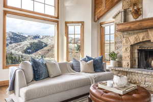 Living room featuring a mountain view, hardwood / wood-style floors, high vaulted ceiling, and a stone fireplace