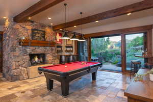 Game room featuring a stone fireplace, beamed ceiling, billiards, bar area, and a mountain view