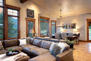 Living room with a chandelier, light hardwood / wood-style floors, and vaulted ceiling